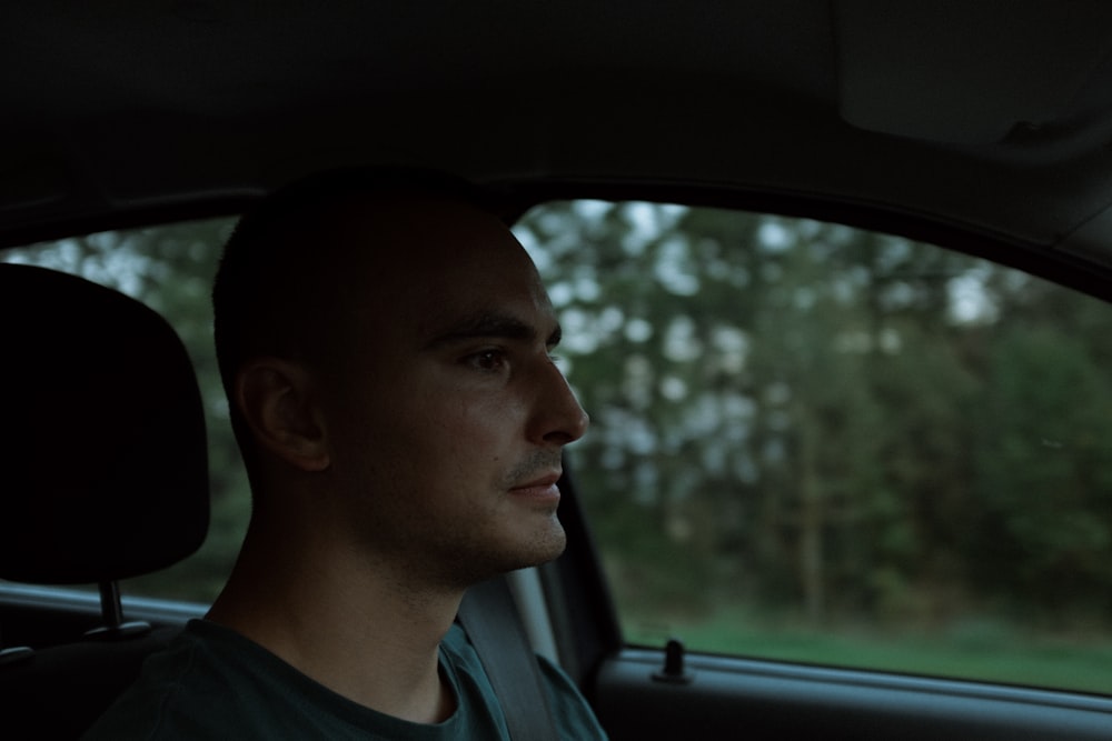 a man sitting in a car looking out the window