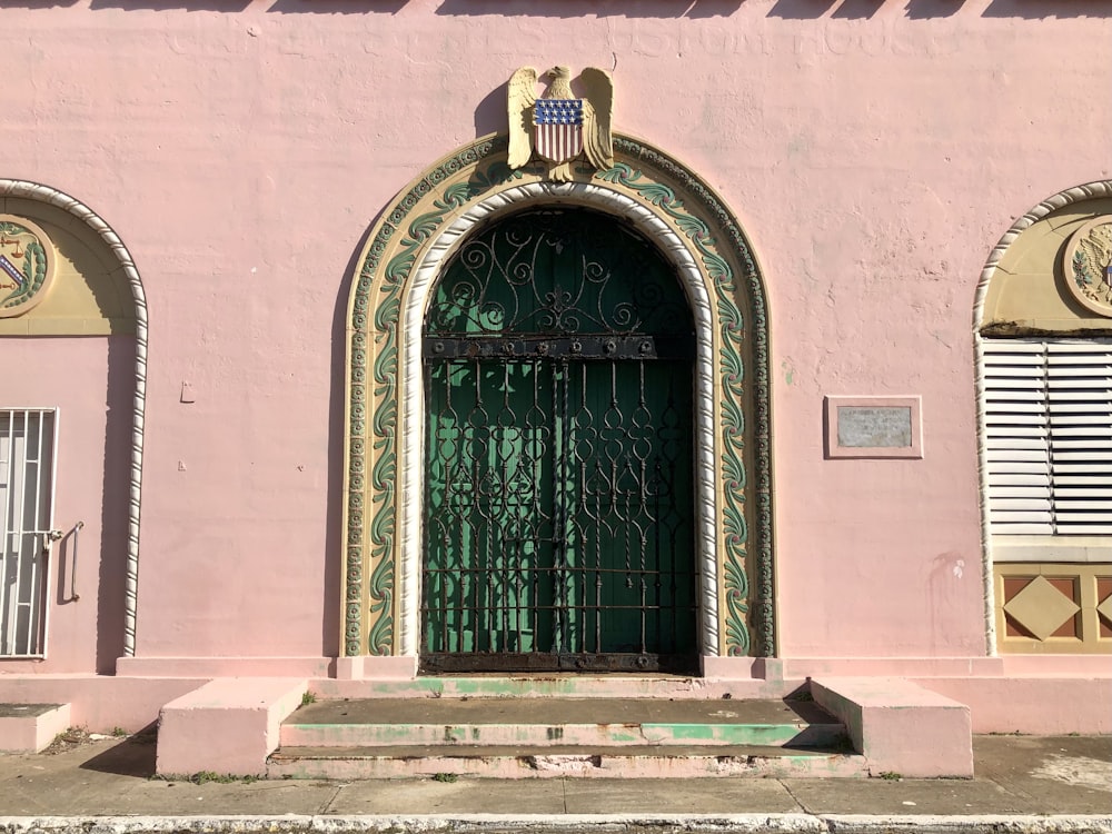 a pink building with a green door and window