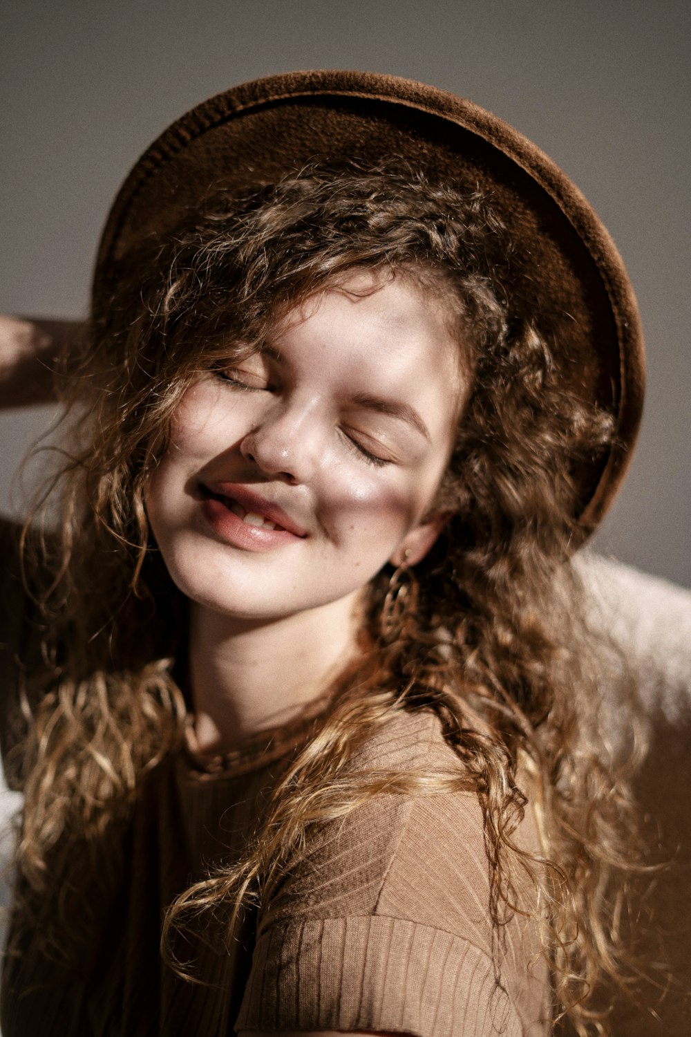 a woman wearing a brown hat and smiling