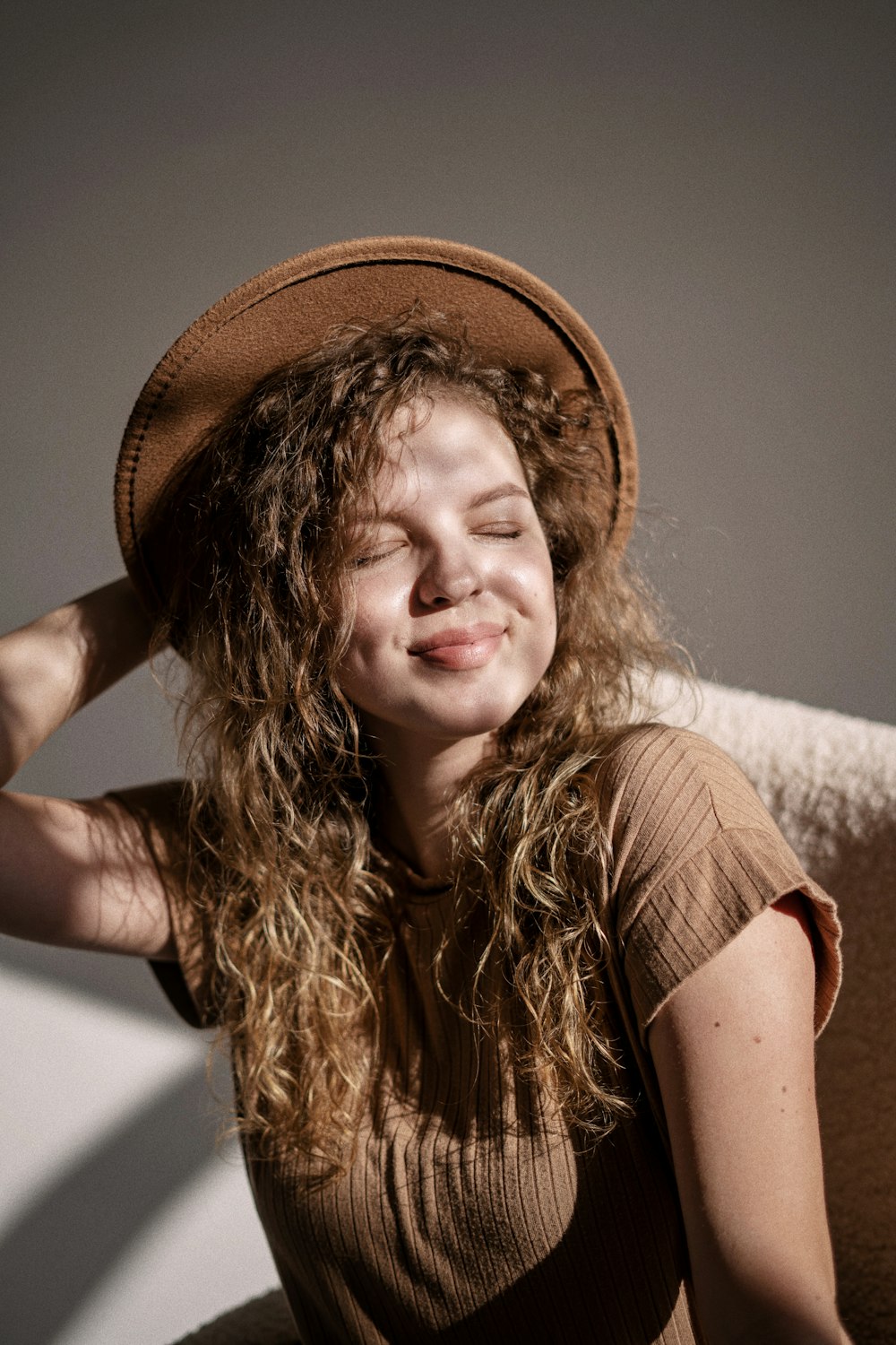 a woman with curly hair wearing a brown hat