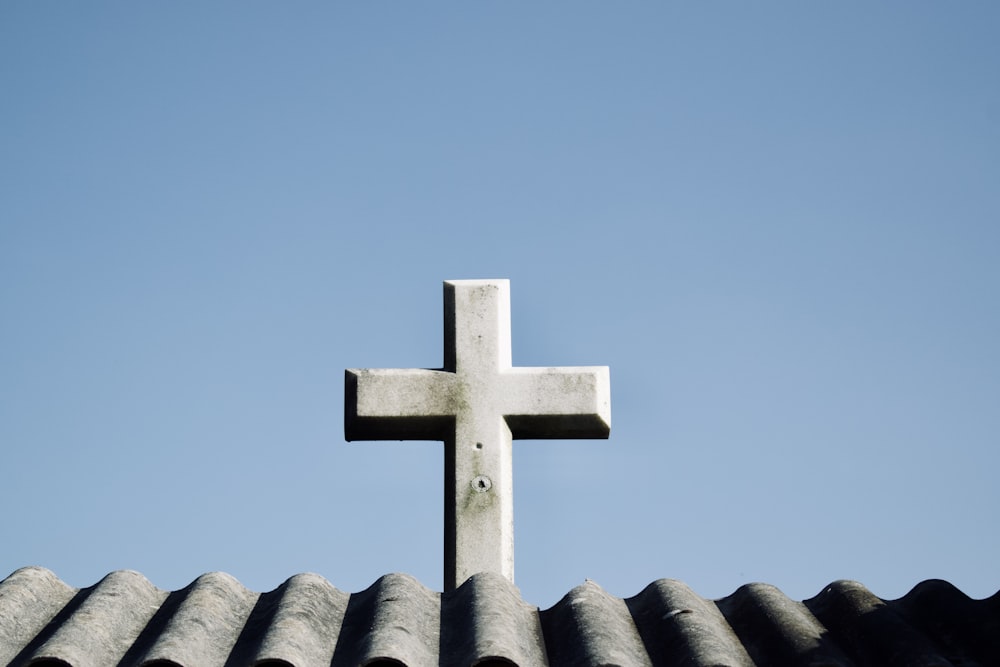 a cross on top of a roof with a blue sky in the background