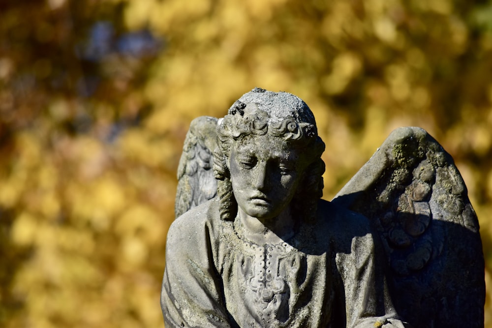 a statue of an angel sitting in front of a tree