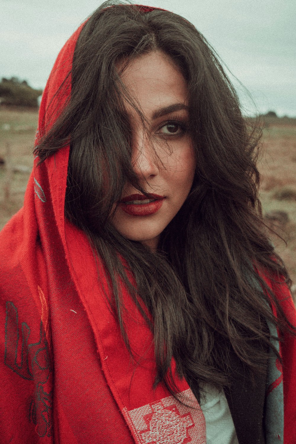 a woman in a red hoodie is standing in a field