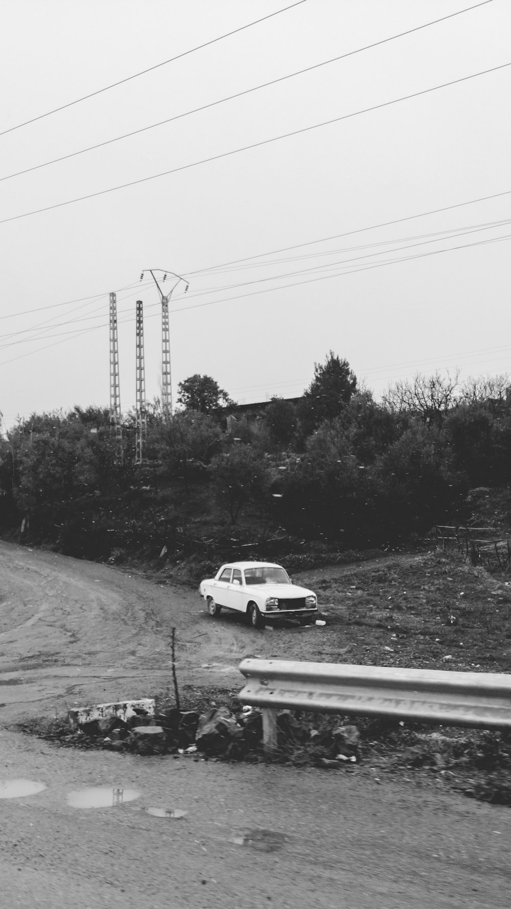 a car driving down a dirt road next to power lines
