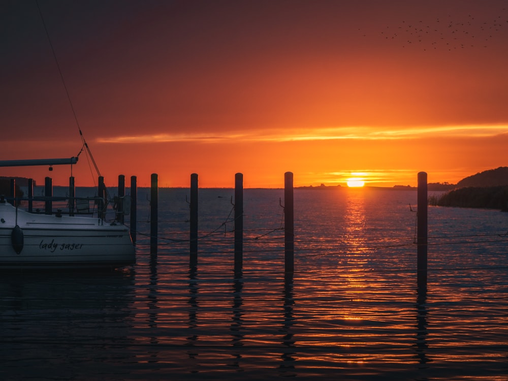 Un bateau est assis dans l’eau au coucher du soleil