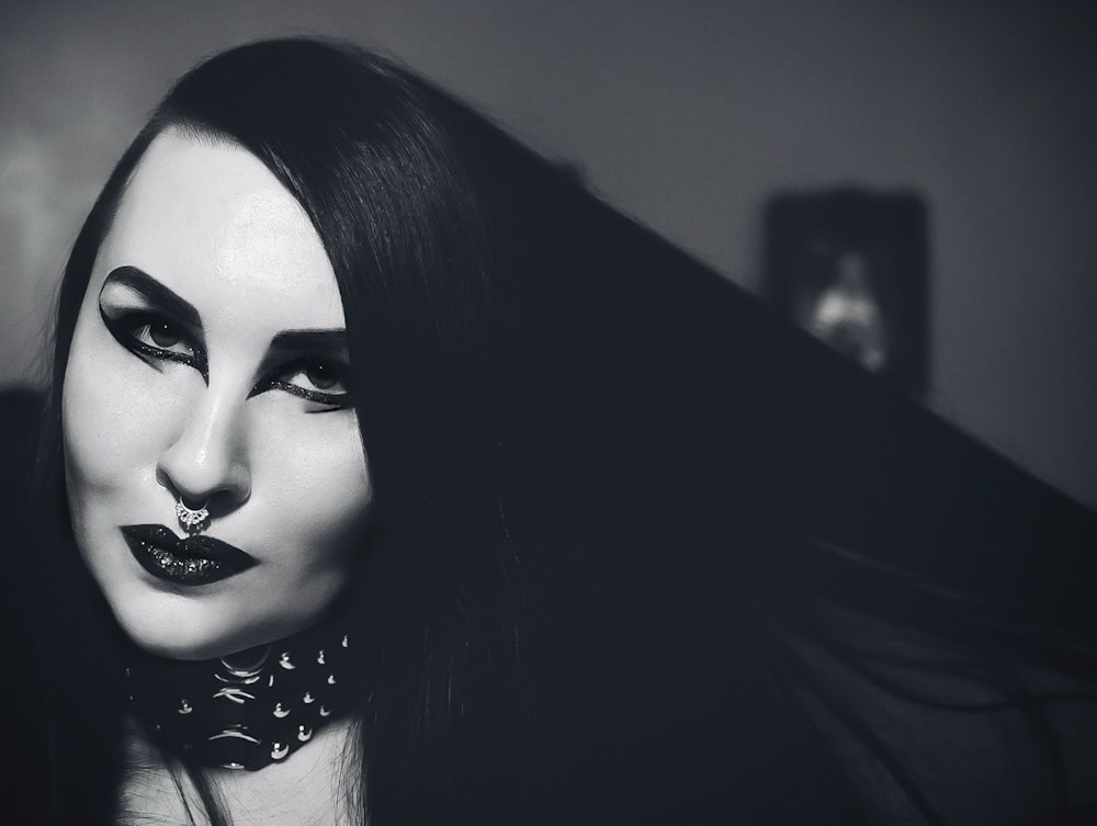a black and white photo of a woman with dark makeup