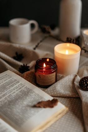 A cozy arrangement of handmade candles and delicate organization journals on a wooden table.