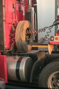 a red semi truck with a tire on the back of it