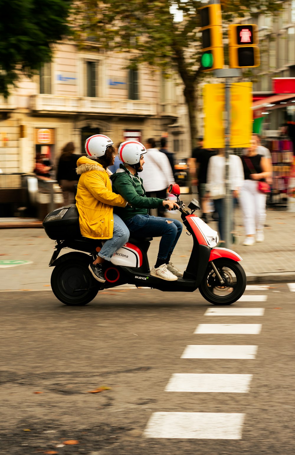 two people riding a scooter on a city street