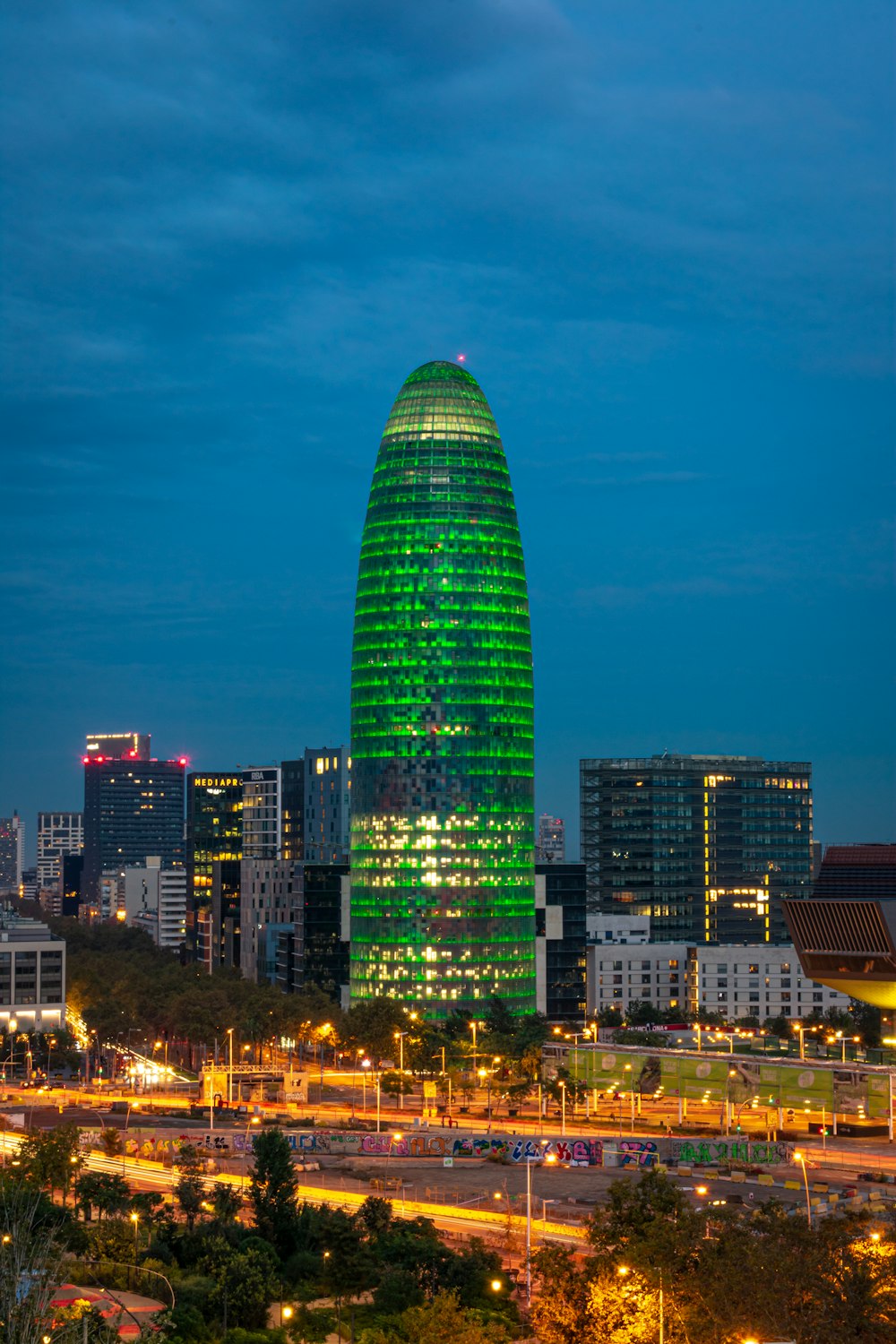 Un edificio verde muy alto en medio de una ciudad