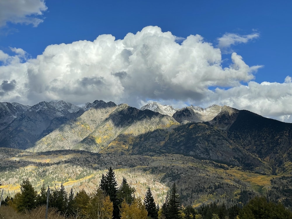 a mountain range with trees and clouds in the background