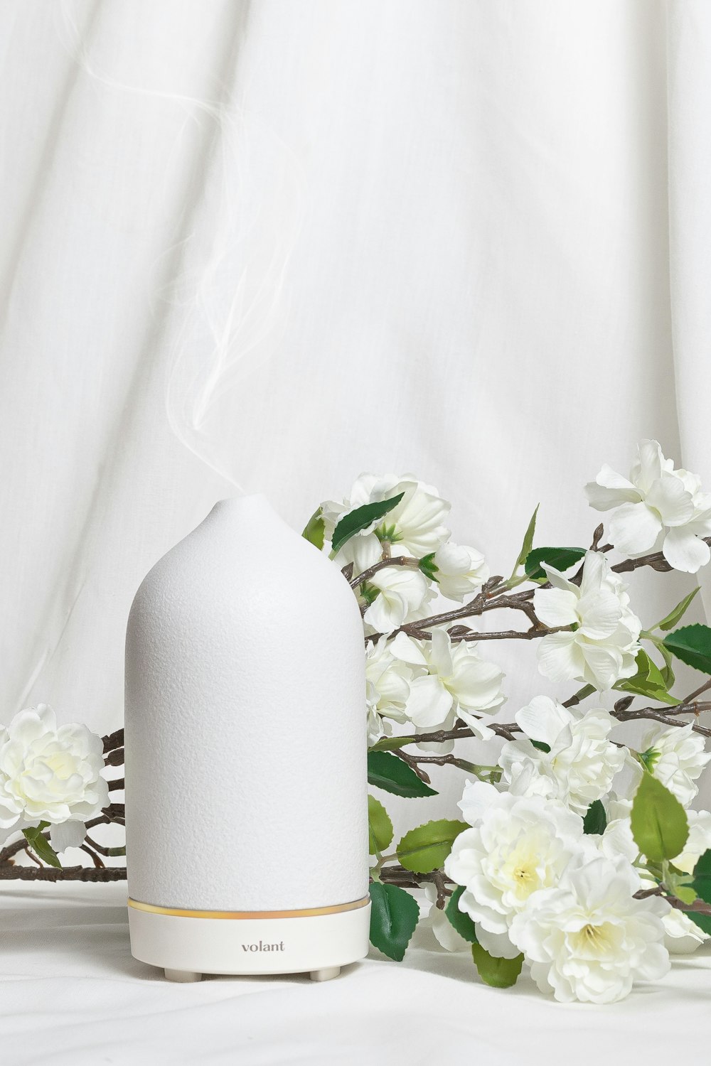 a white vase sitting on top of a white table