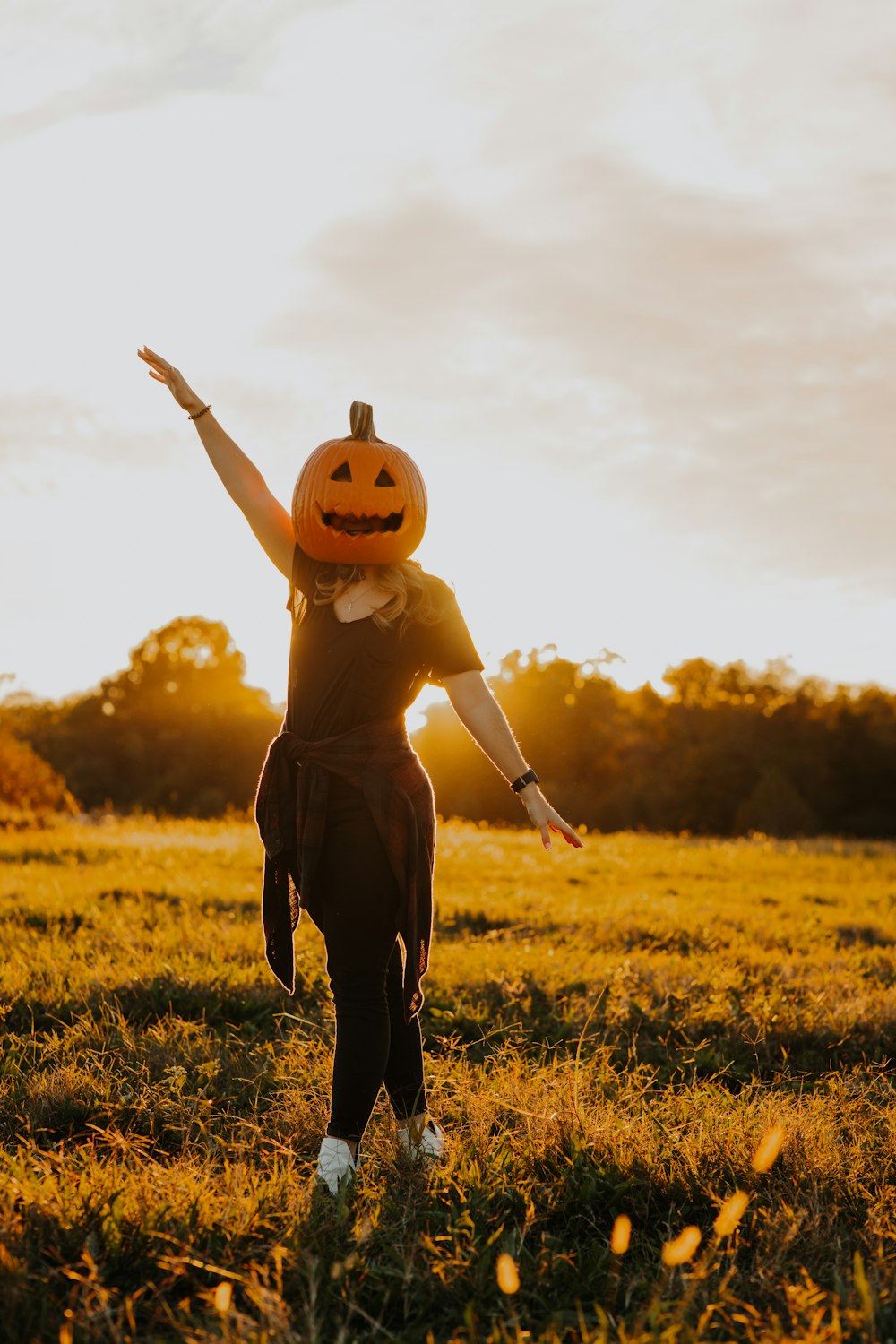 a young girl wearing a pumpkin hat in a field