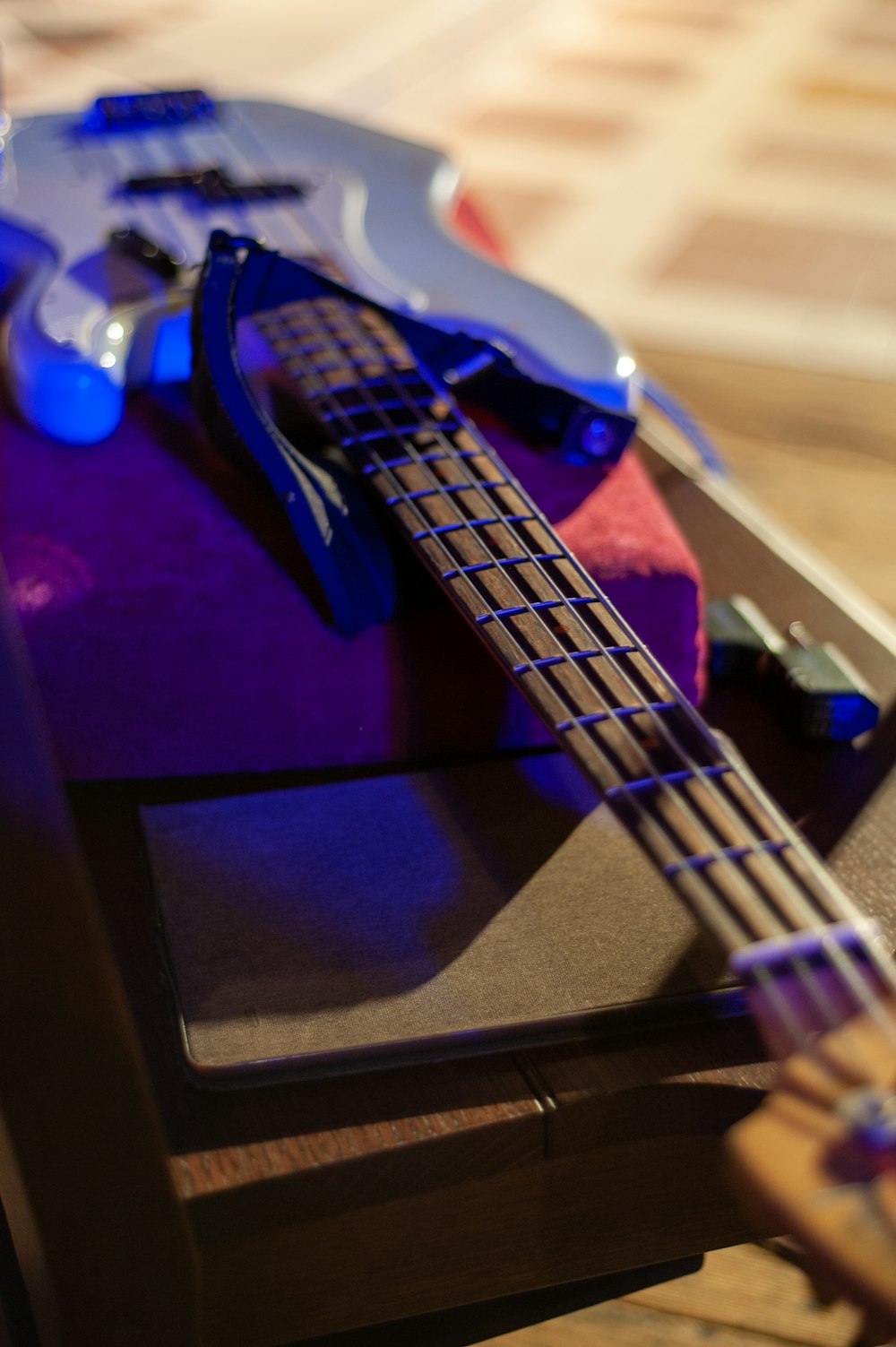 a blue bass guitar sitting on top of a wooden table