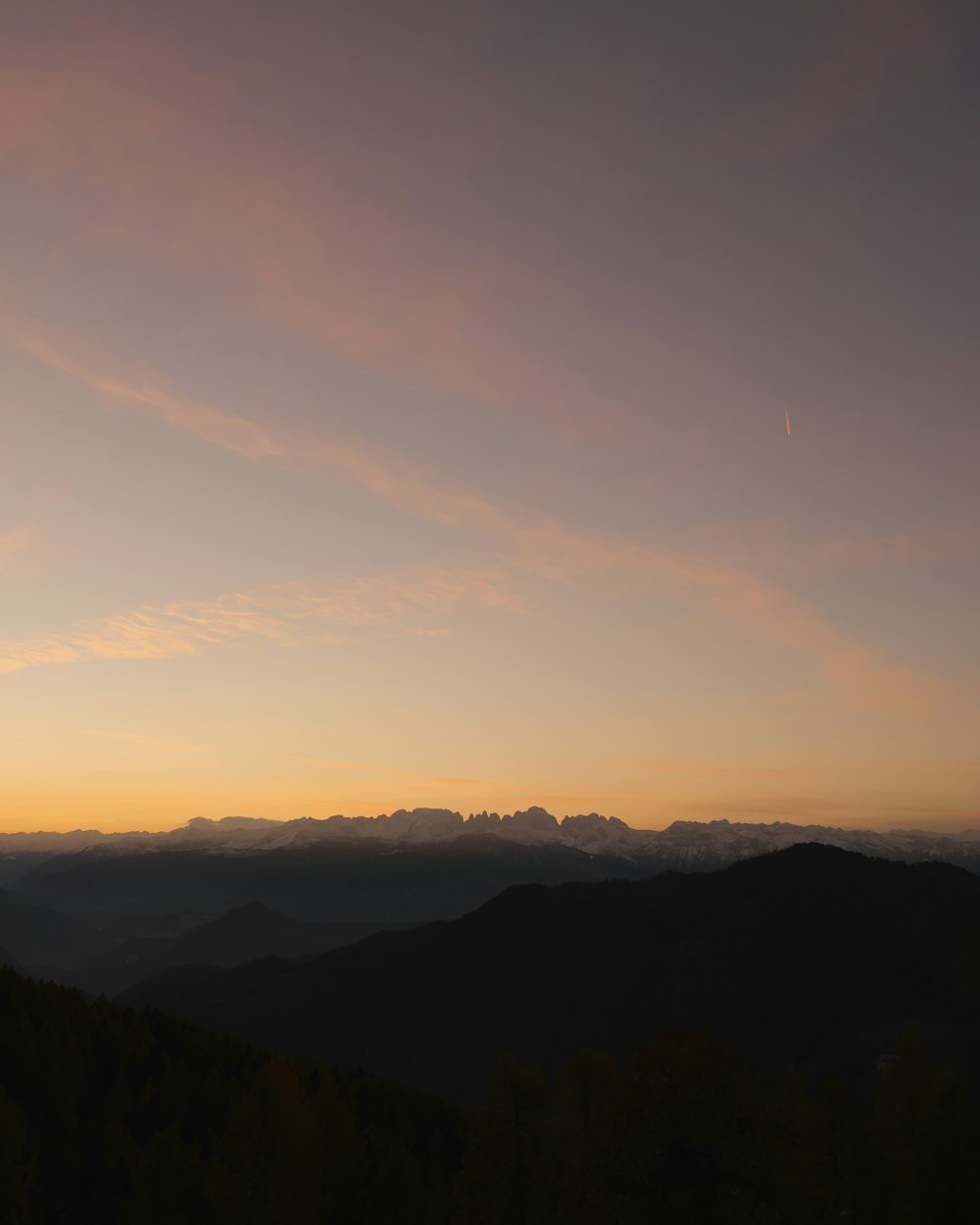 the sun is setting over a mountain range