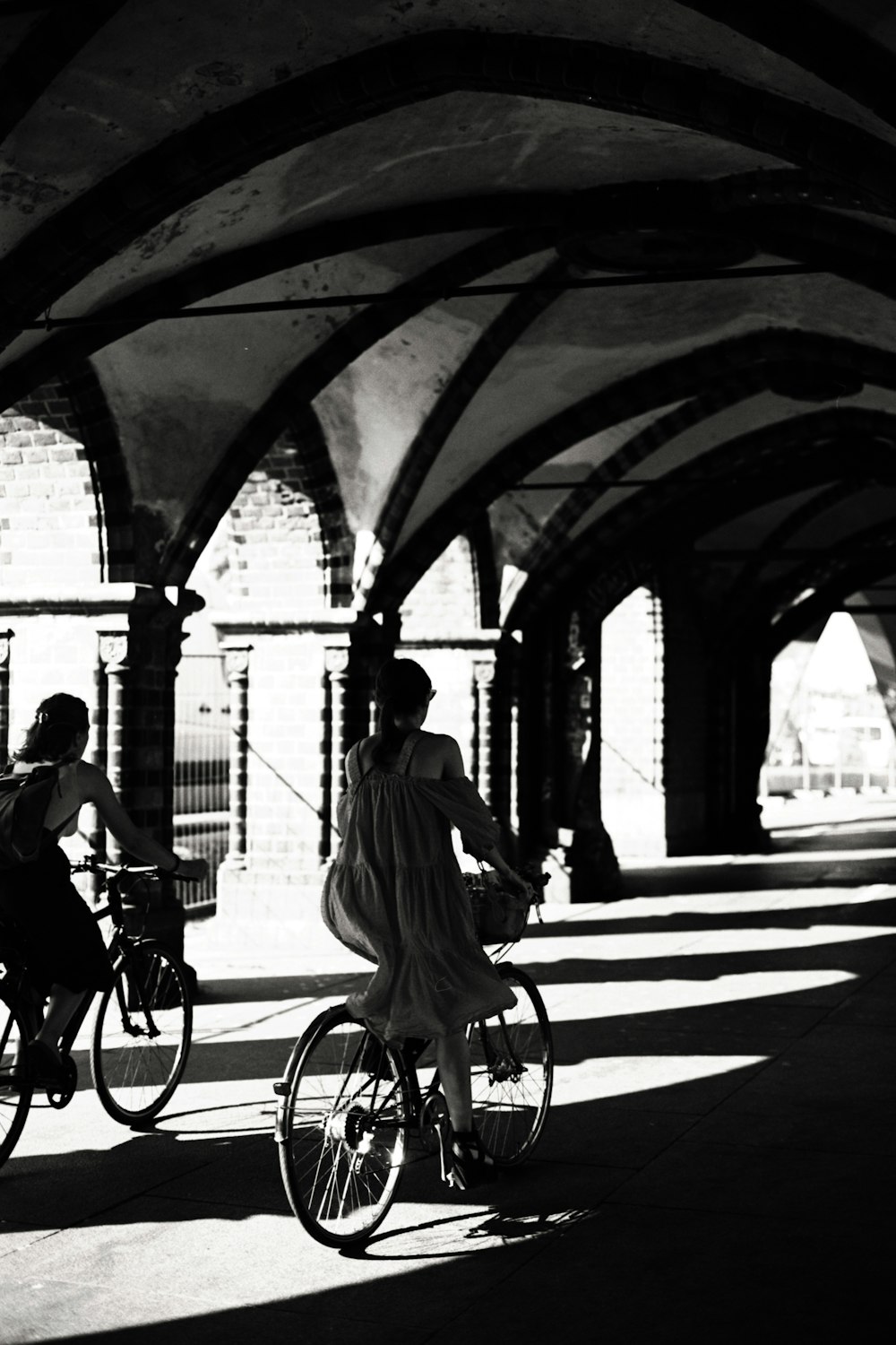 a black and white photo of two people riding bicycles