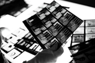 A close-up of hands sorting through old photo negatives and prints.