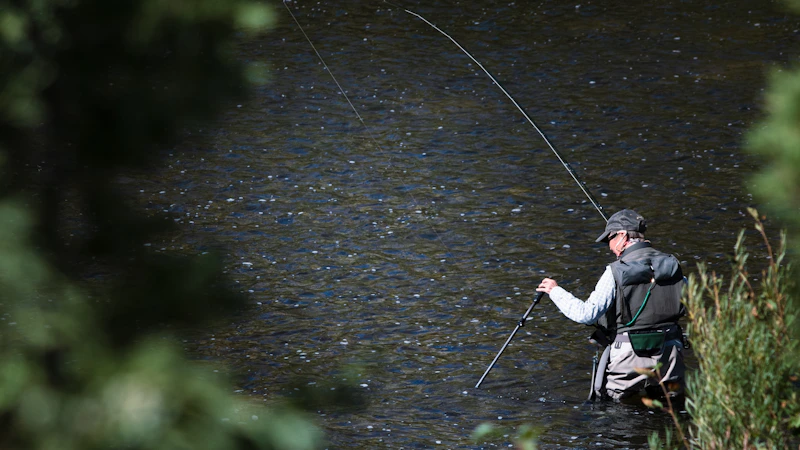 fly fisherman in a river holding a rod