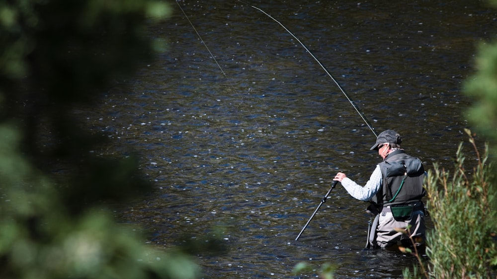 Un hombre parado en un río sosteniendo una caña de pescar