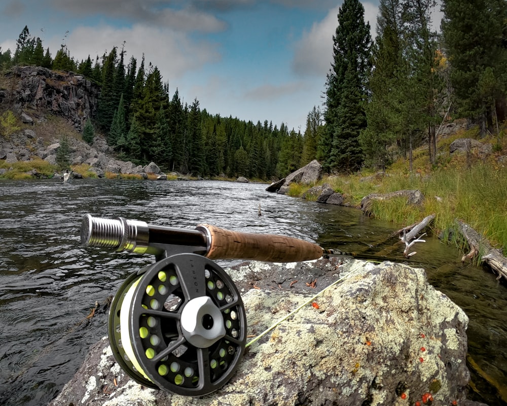 a fly fishing rod on a rock next to a river