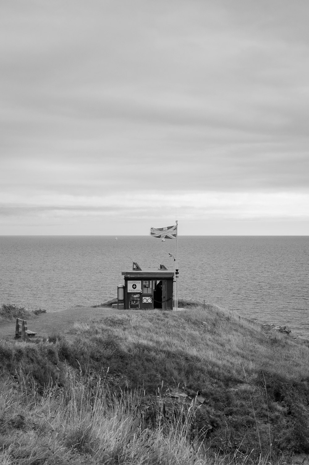 a black and white photo of a small hut by the ocean