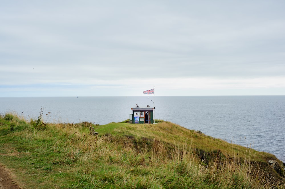 a small house sitting on top of a hill next to the ocean