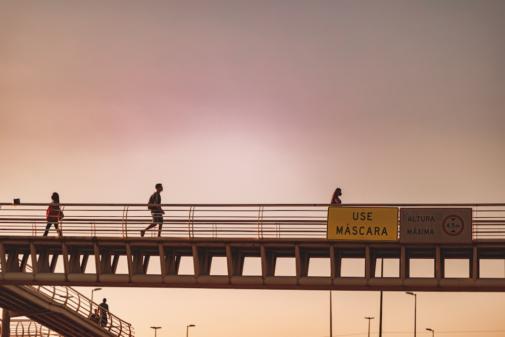 a group of people walking across a bridge