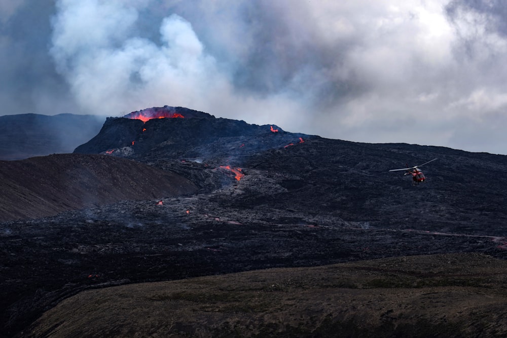 a helicopter flying over a mountain covered in lava