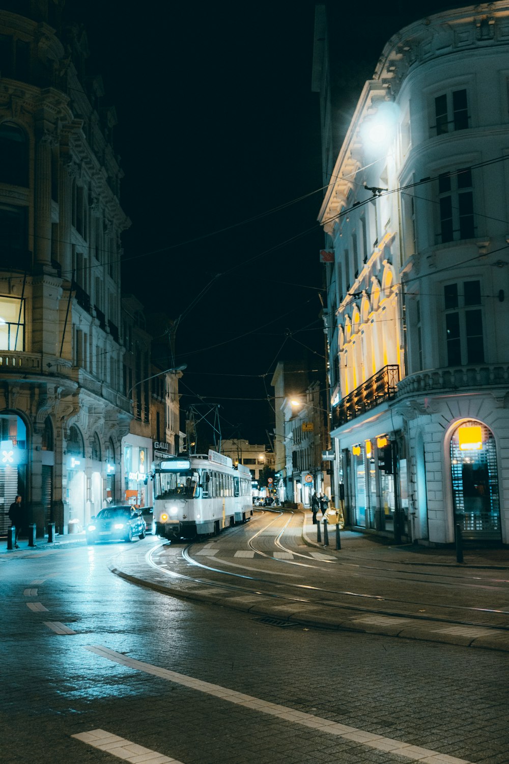 a city street at night with a bus on the road