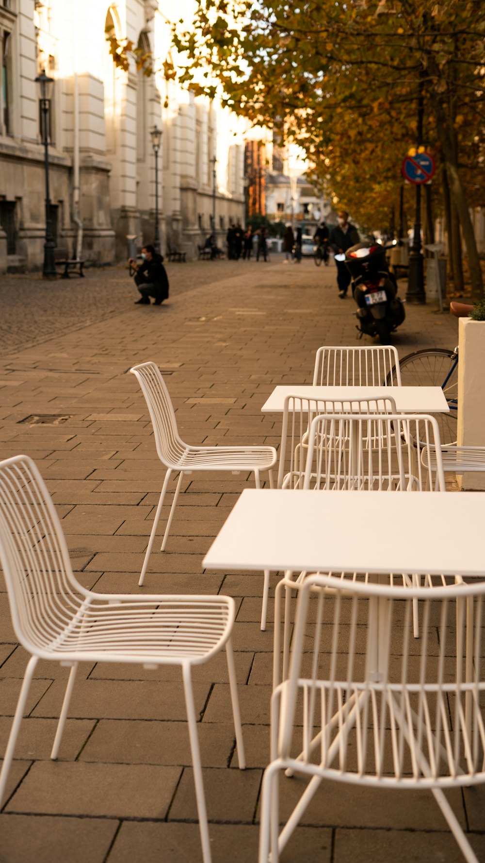 una fila de mesas y sillas blancas sentadas en una acera