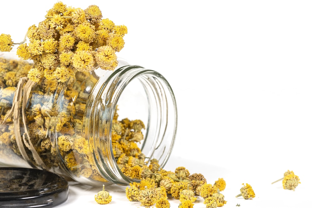 a jar filled with yellow flowers sitting on top of a table