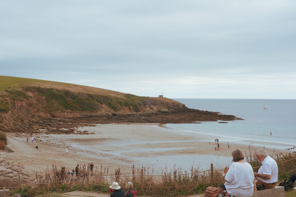 a group of people sitting on top of a hill next to the ocean