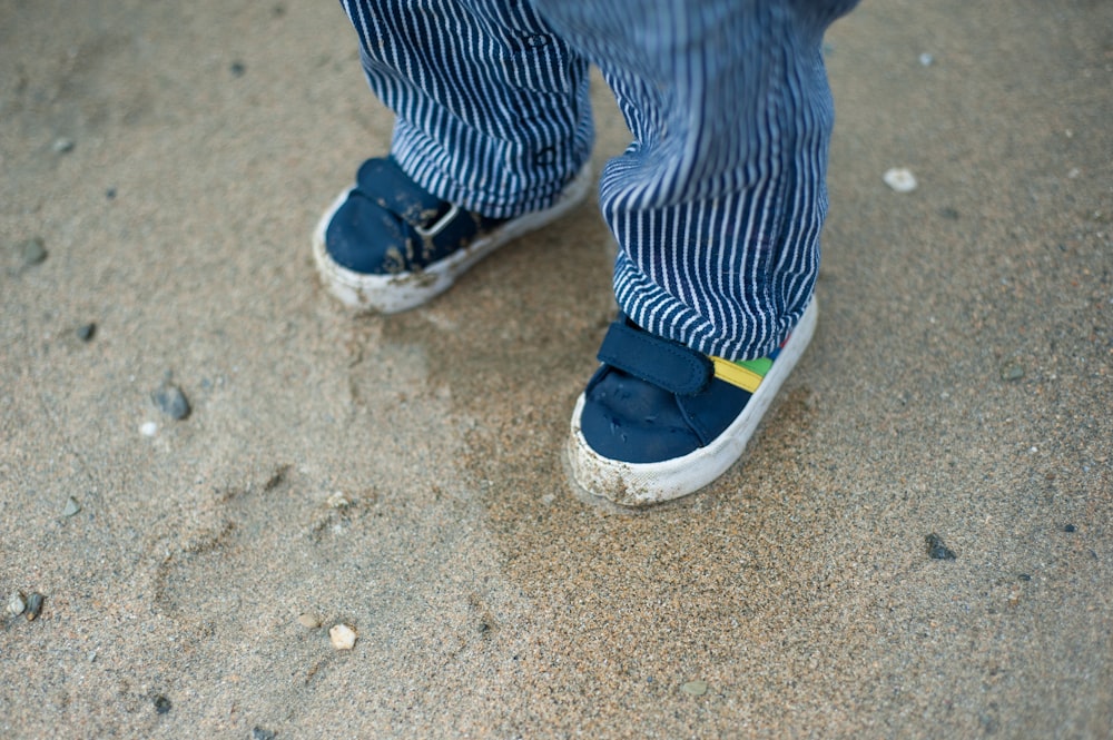 a close up of a person's shoes on the sand
