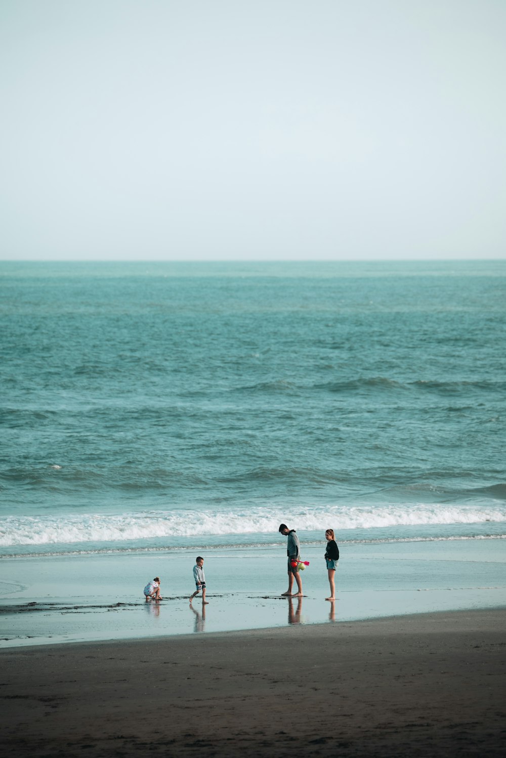 a group of people walking along a beach next to the ocean