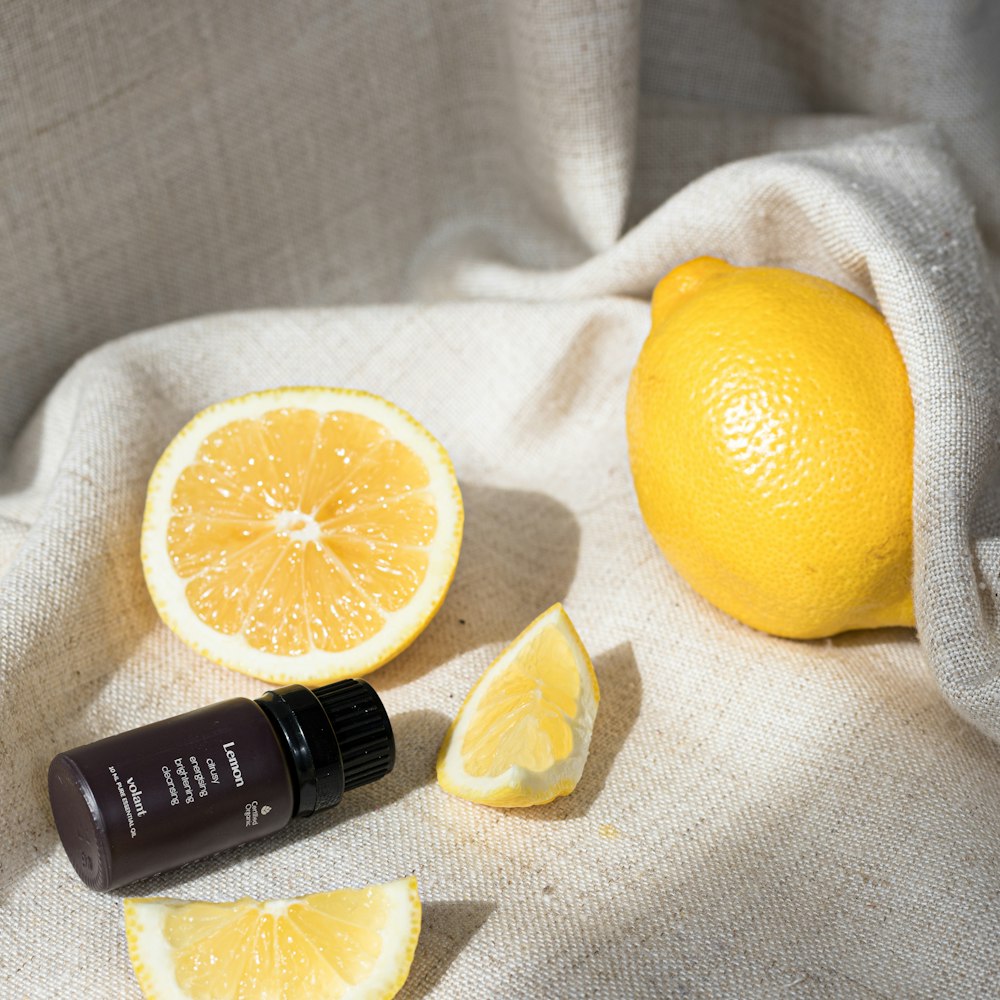 a bottle of essential oil next to a sliced lemon