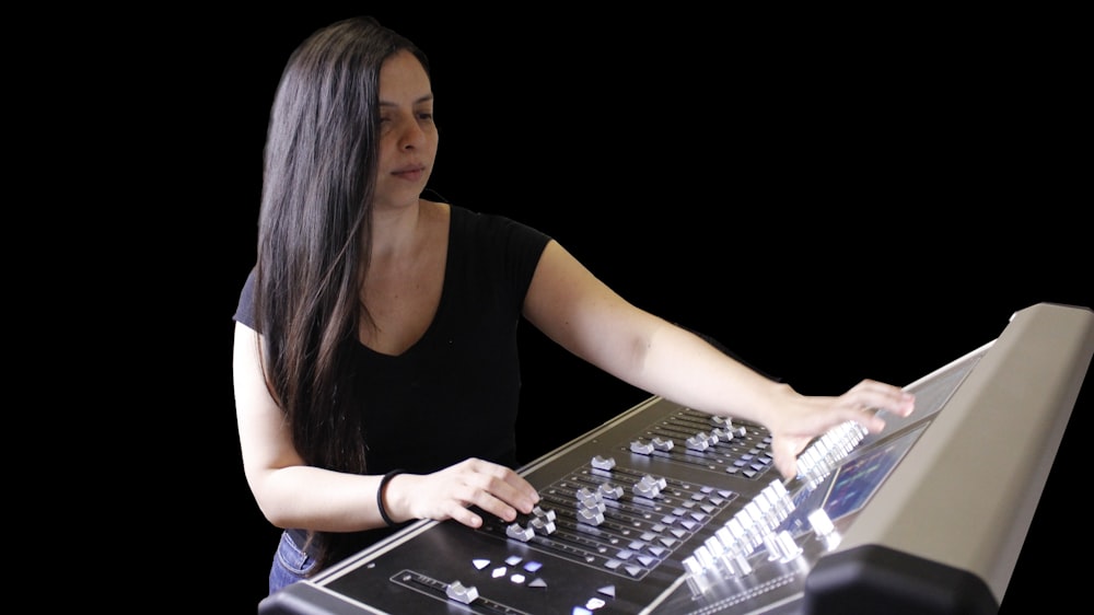 a woman is playing a sound board on a black background