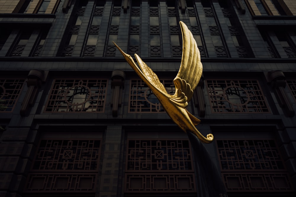 a gold sculpture of a bird is in front of a building