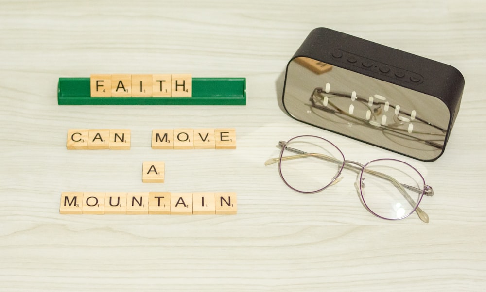 a pair of glasses sitting next to some scrabble letters