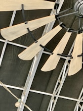 Wooden fan blades attached to a central hub mounted on an industrial-style metal ceiling. The structure consists of metal beams and a string of lights with a single exposed bulb.