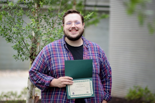 A smiling business owner holding approved license papers outside their shop.