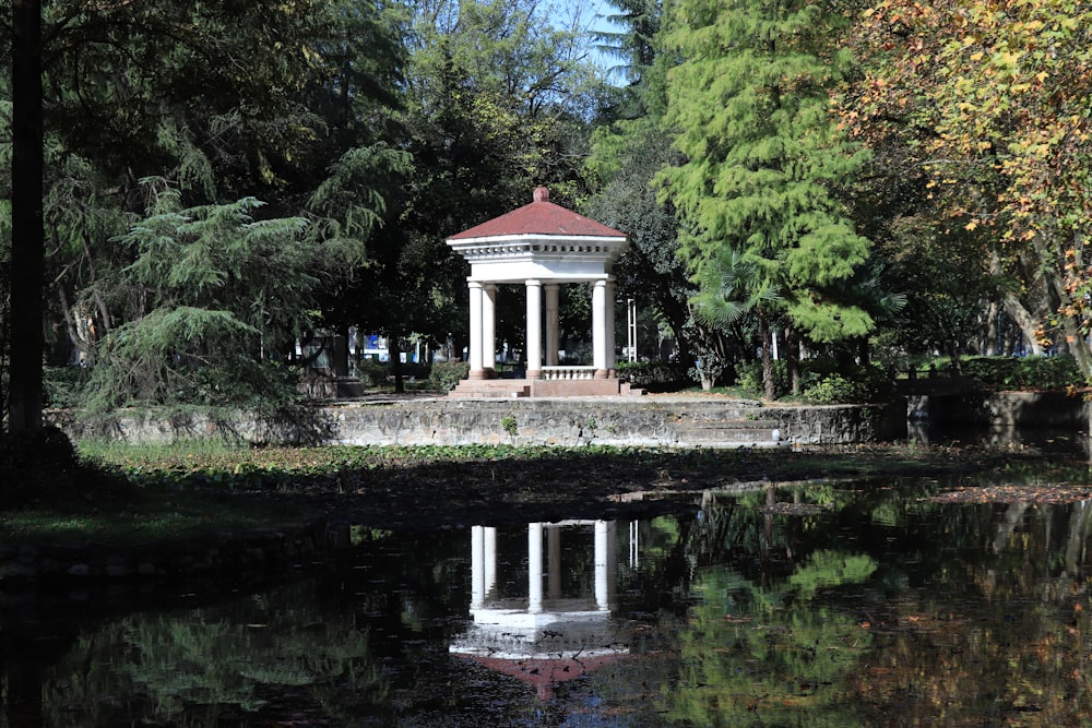 a gazebo in the middle of a pond surrounded by trees