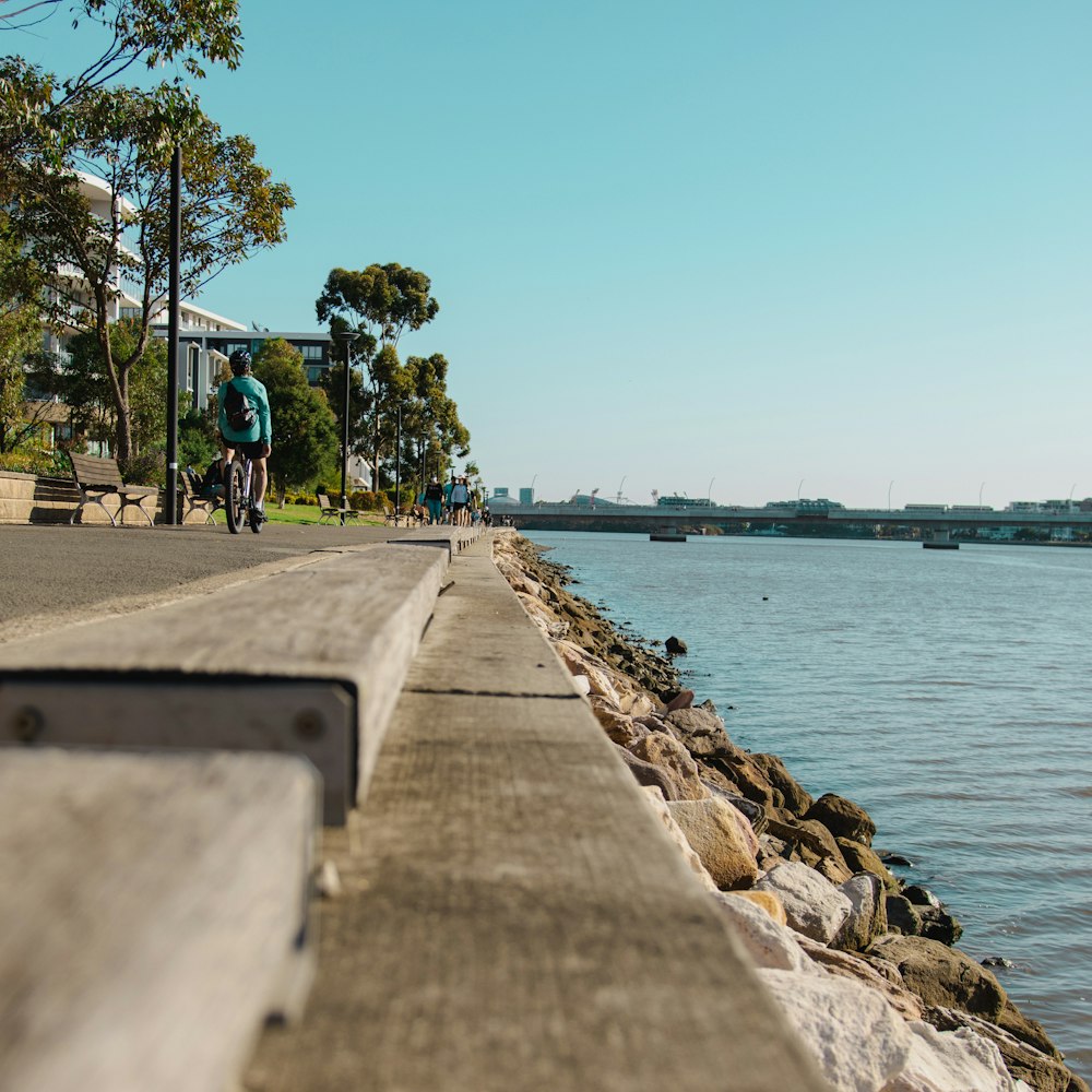 a man riding a bike down a street next to a body of water