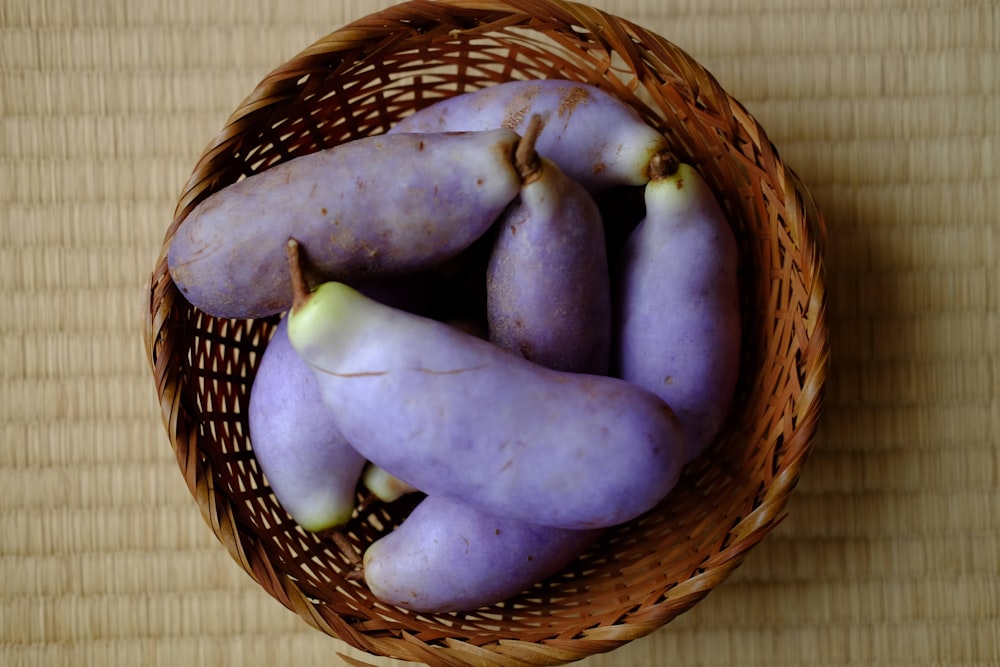 a basket filled with purple fruit sitting on top of a wooden table