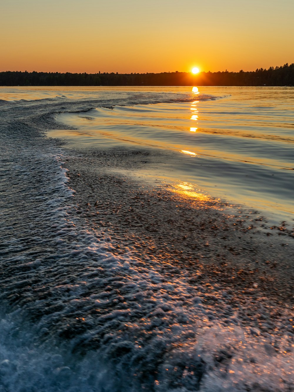 Die Sonne geht über dem Wasser am Strand unter