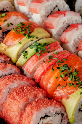 A vibrant close-up of a colorful sushi roll topped with fresh salmon and avocado slices.