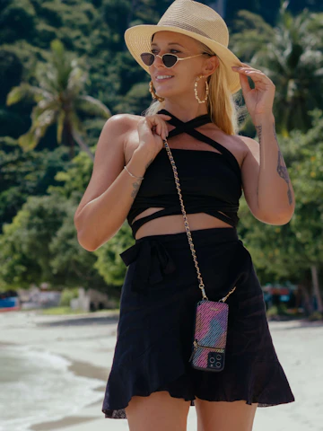 A stylish woman carrying a compact crossbody bag in a sunny urban setting.
