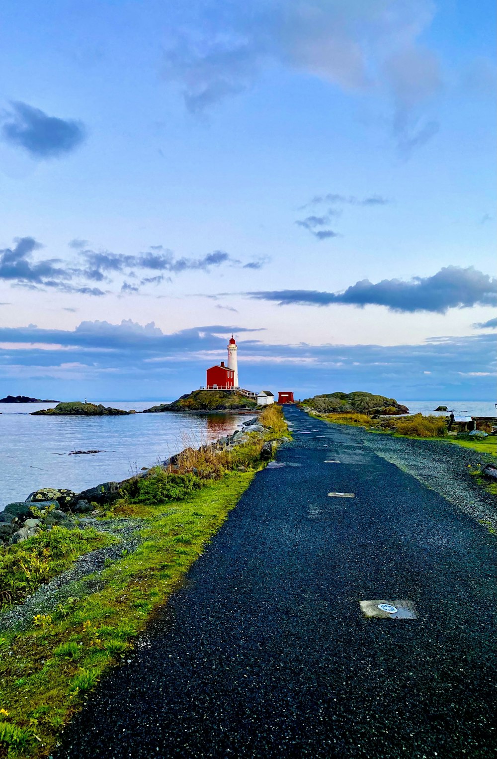 a road leading to a light house on an island