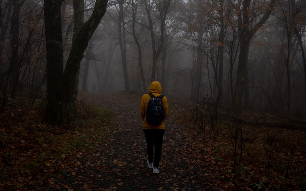 a person in a yellow jacket is walking through the woods