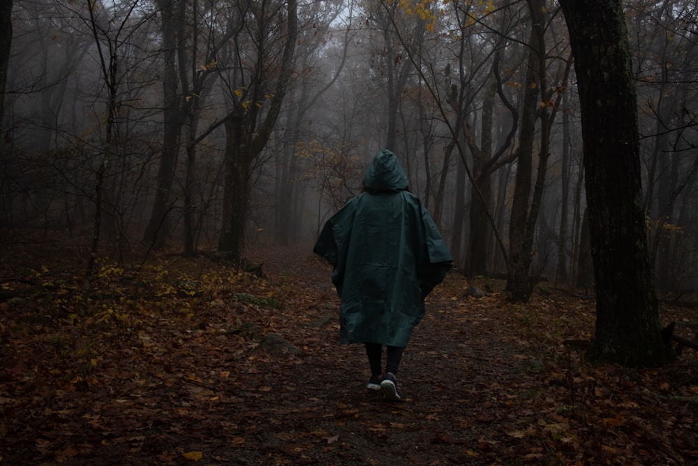 a person in a raincoat walking through a forest