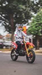 a man riding a red motorcycle down a street